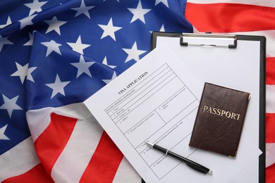 Visa application form, clipboard and passport on American flag, top view