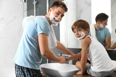 Dad and son washing razors in bathroom