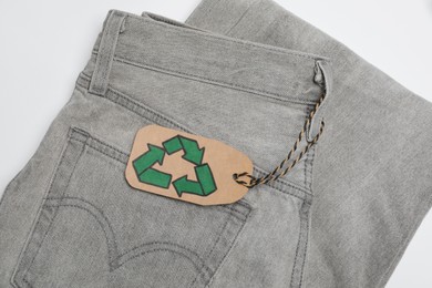Jeans with recycling label on white background, top view