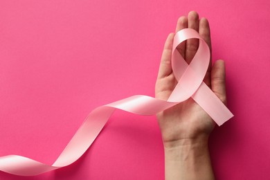 Photo of Woman holding pink ribbon on color background, top view with space for text. Breast cancer awareness concept