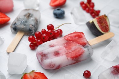 Tasty refreshing berry ice pops on white table, closeup