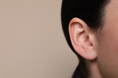 Woman on grey background, closeup of ear. Space for text