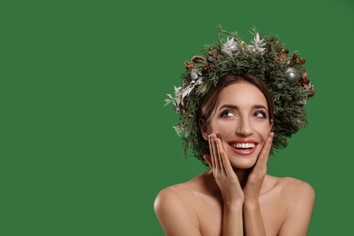 Photo of Emotional young woman wearing Christmas wreath on green background. Space for text