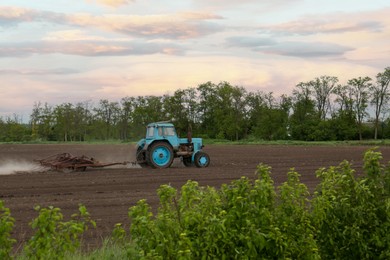 Tractor plowing agricultural field under cloudy sky