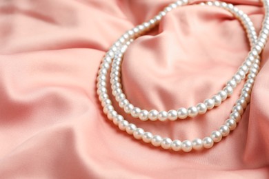 Elegant necklace with pearls on pink silk, closeup