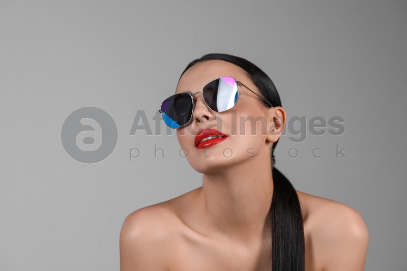Attractive woman in fashionable sunglasses against grey background. Space for text