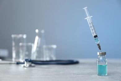 Syringe and vial on light grey table. Space for text