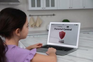 Little girl having access restriction by parental control on laptop in kitchen. Child safety