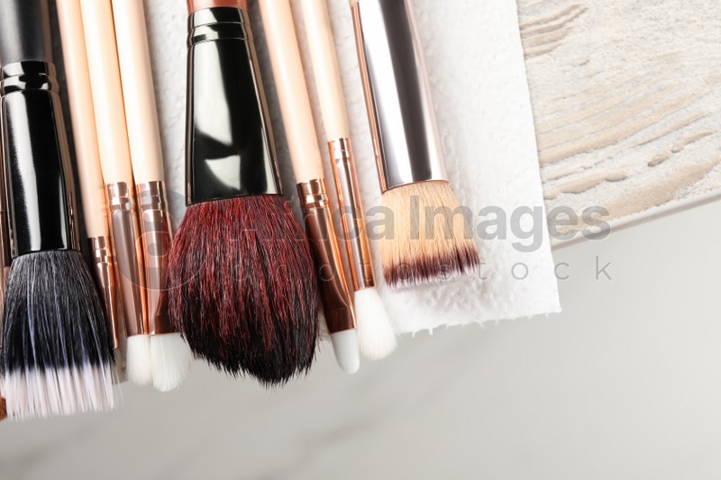 Photo of Set of different makeup brushes drying after cleaning on table, closeup