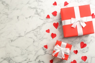 Beautiful gift boxes and paper hearts on marble table, flat lay with space for text. Valentine's Day celebration
