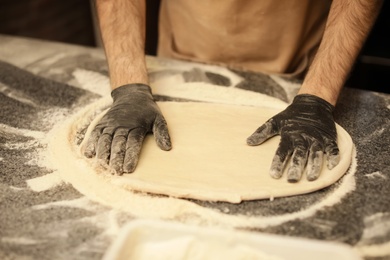Man making pizza at table, closeup view