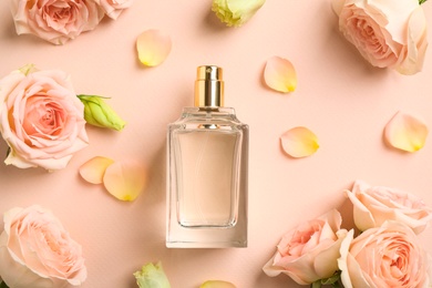 Bottle of perfume, beautiful flowers and petals on beige background, flat lay