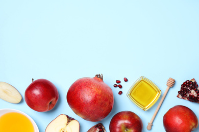Honey, apples and pomegranates on light blue background, flat lay with space for text. Rosh Hashanah holiday