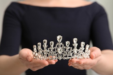 Photo of Young woman holding luxurious tiara, closeup view