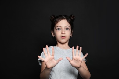 Photo of Little girl feeling fear on black background