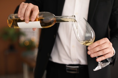 Man pouring delicious wine into glass indoors
