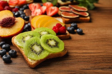 Tasty toast with butter and kiwi slices on wooden table, closeup. Space for text