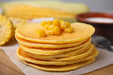 Stack of tasty corn pancakes with sweet kernels served on wooden table, closeup
