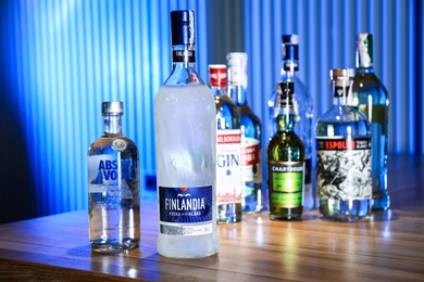Photo of MYKOLAIV, UKRAINE - SEPTEMBER 24, 2019: Bottles of global vodka brands on wooden counter in bar. Space for text