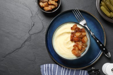 Potato puree and tasty fried cracklings served on black table, flat lay with space for text. Cooked pork lard