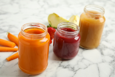 Healthy baby food in jars and fresh ingredients on white marble table