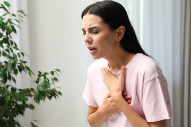 Young woman suffering from breathing problem indoors