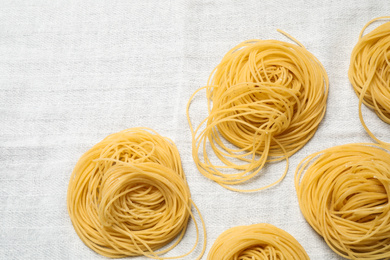 Capellini pasta on white tablecloth, flat lay