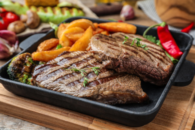 Delicious beef steaks served on wooden table, closeup
