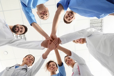 Team of medical workers holding hands together in hospital, bottom view. Unity concept