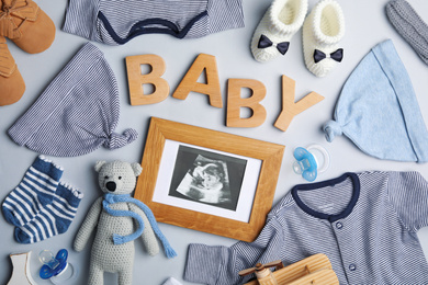 Flat lay composition with child's clothes, ultrasound photo and word Baby on light background