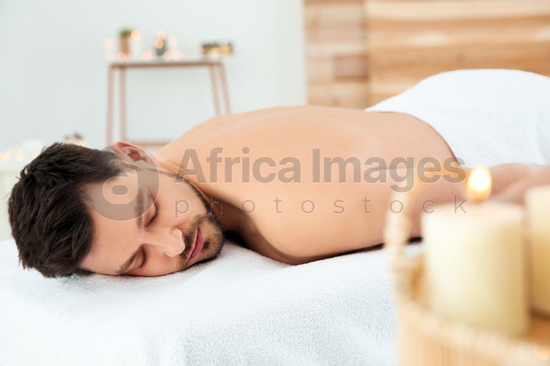 Photo of Handsome man relaxing on massage table in spa salon