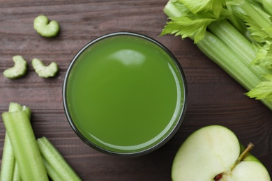 Glass of celery juice and fresh ingredients on wooden table, flat lay