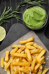 Serving board with french fries, avocado dip, lime and rosemary on cloth, flat lay