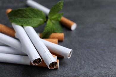 Menthol cigarettes and mint on grey table, closeup. Space for text