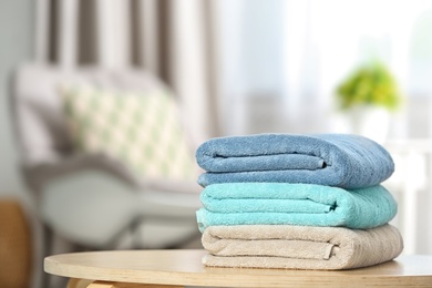 Stack of folded clean soft towels on table indoors. Space for text