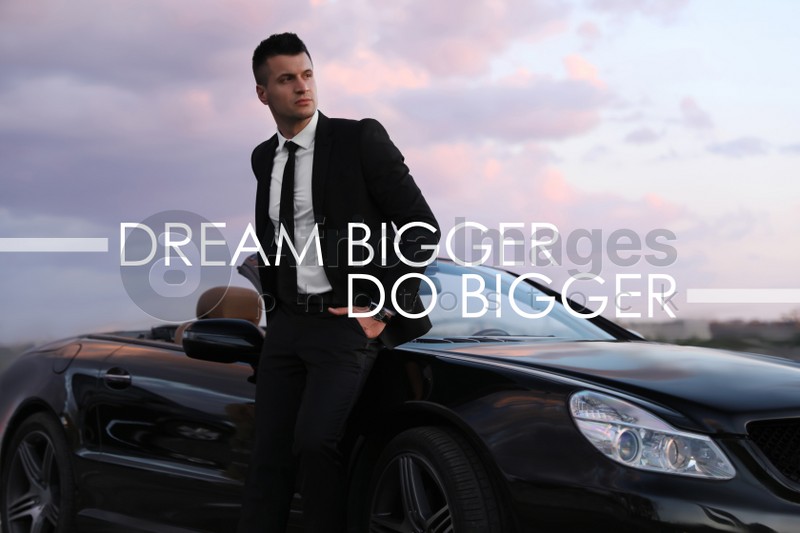 Image of Dream Bigger Do Bigger. Inspirational quote motivating to set life goals freely and forget about reasons that can hold back. Text against successful businessman with luxury car