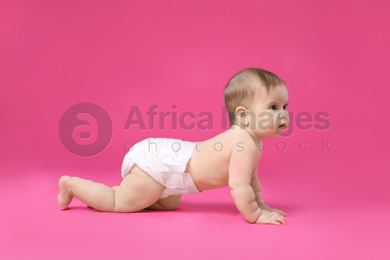 Cute little baby in diaper crawling on pink background