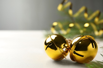 Golden sleigh bells on white table, closeup. Space for text