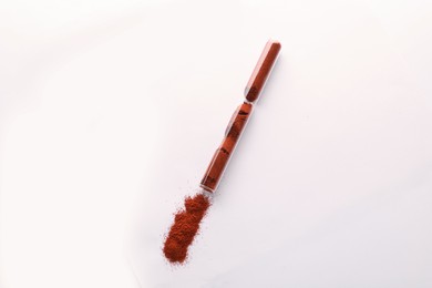 Glass tube with paprika on white background, top view