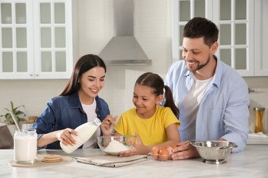Happy family cooking together at table in kitchen. Adoption concept
