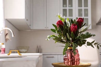 Photo of Bouquet with beautiful protea flowers in kitchen, space for text. Interior design