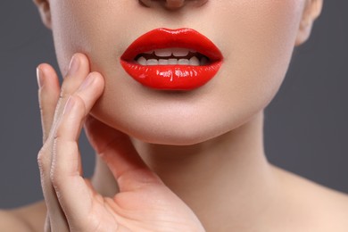 Photo of Young woman with beautiful red lips on grey background, closeup