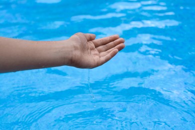 Girl pouring water from hand in pool, closeup