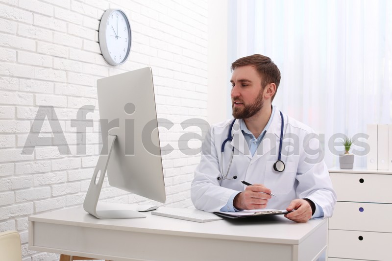 Photo of Pediatrician consulting patient online at table in clinic