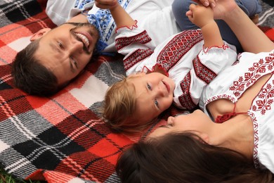 Happy family in national clothes lying on blanket together, closeup
