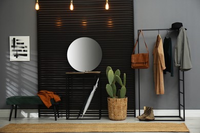 Photo of Hallway interior with stylish furniture, clothes and big houseplant
