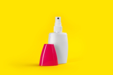 Bottle with insect repellent spray on yellow background