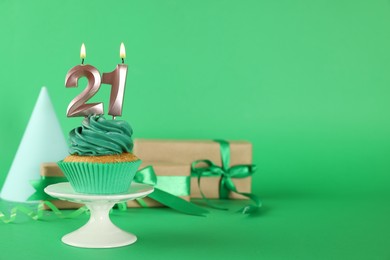 Delicious cupcake with number shaped candles on green background, space for text. Coming of age party - 21th birthday