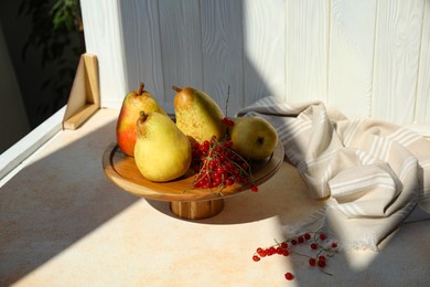 Stand with juicy pears, red currants and double-sided backdrop in photo studio