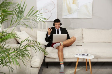 Photo of Businessman in jacket and underwear having videocall on laptop at home